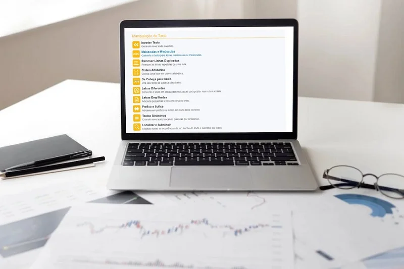 A imagem mostra um notebook em cima de uma mesa, onde de lado temos um óculos e de outro uma agenda com uma caneta.