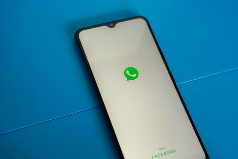 Tela em brando de um smartphone sobre uma mesa azul mostrando o ícone do WhatsApp