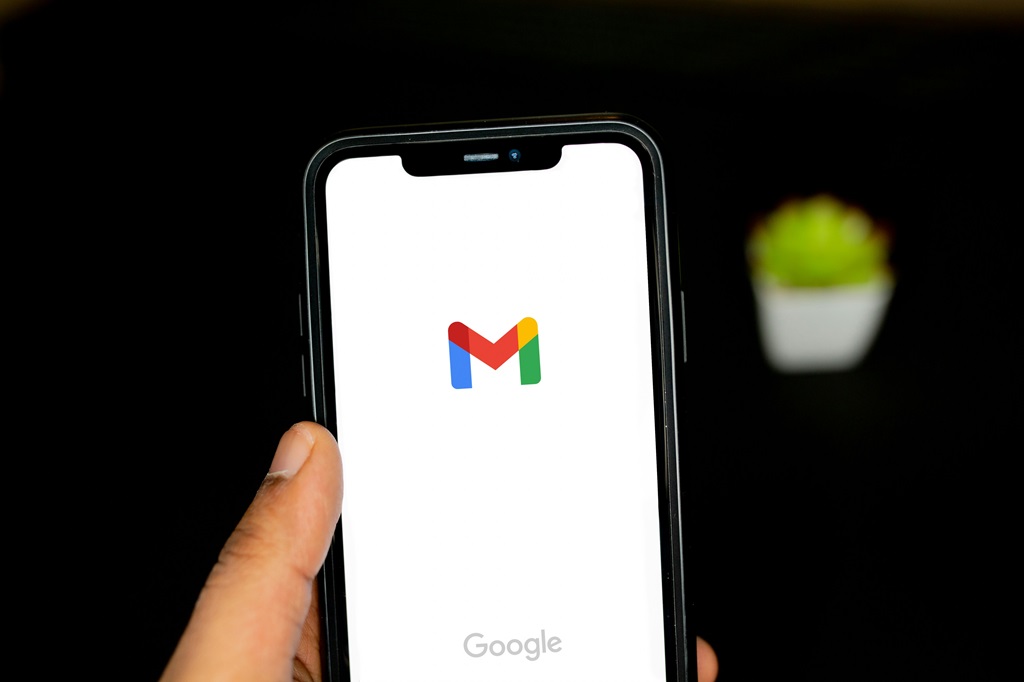 Mão segurando um smartphone com a tela mostrando logo do Gmail. Imagem Solen Feyissa - Unsplash