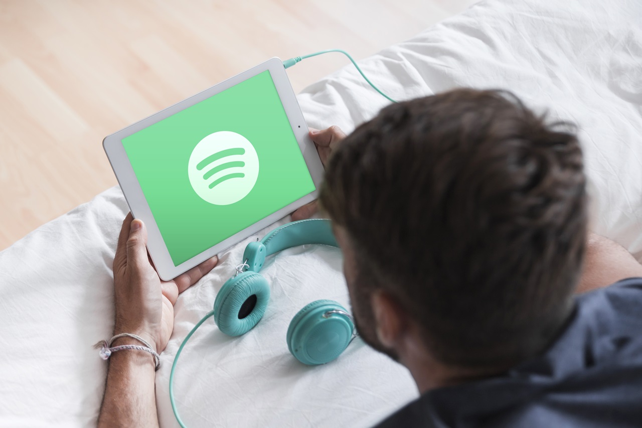 Jovem segurando tablet no app do Spotify. Imagem de Freepik