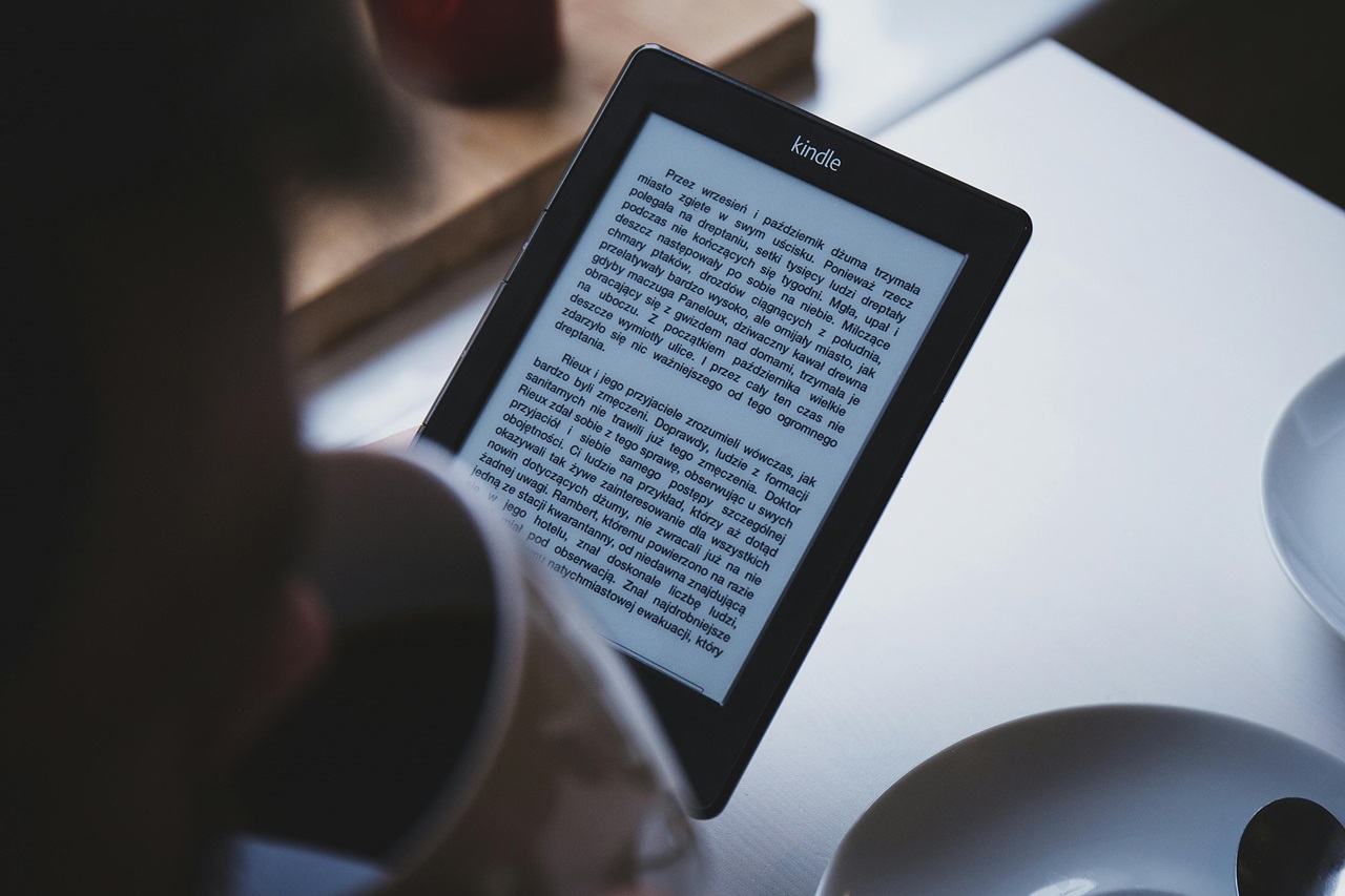 A imagem mostra alguém segurando um kindle, dispositivo de leitura de e-books da Amazon, mostrando uma página de leitura. Imagem: freestocks.org / Pexels.