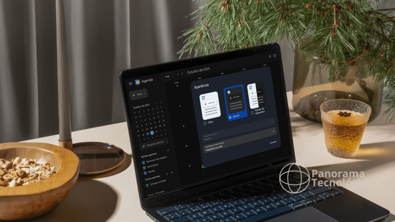 A imagem mostra um laptop em uma mesa, com a tela exibindo a interface do Google Agenda no modo escuro. A data na tela é outubro de 2024. Ao lado do laptop, há uma tigela de madeira com cereais, uma vela em um suporte, e um copo de vidro com uma bebida âmbar, possivelmente chá, decorado com uma estrela de anis. Atrás do laptop, há um vaso de vidro com galhos de pinheiro. No canto inferior direito da imagem, há um logotipo com o texto