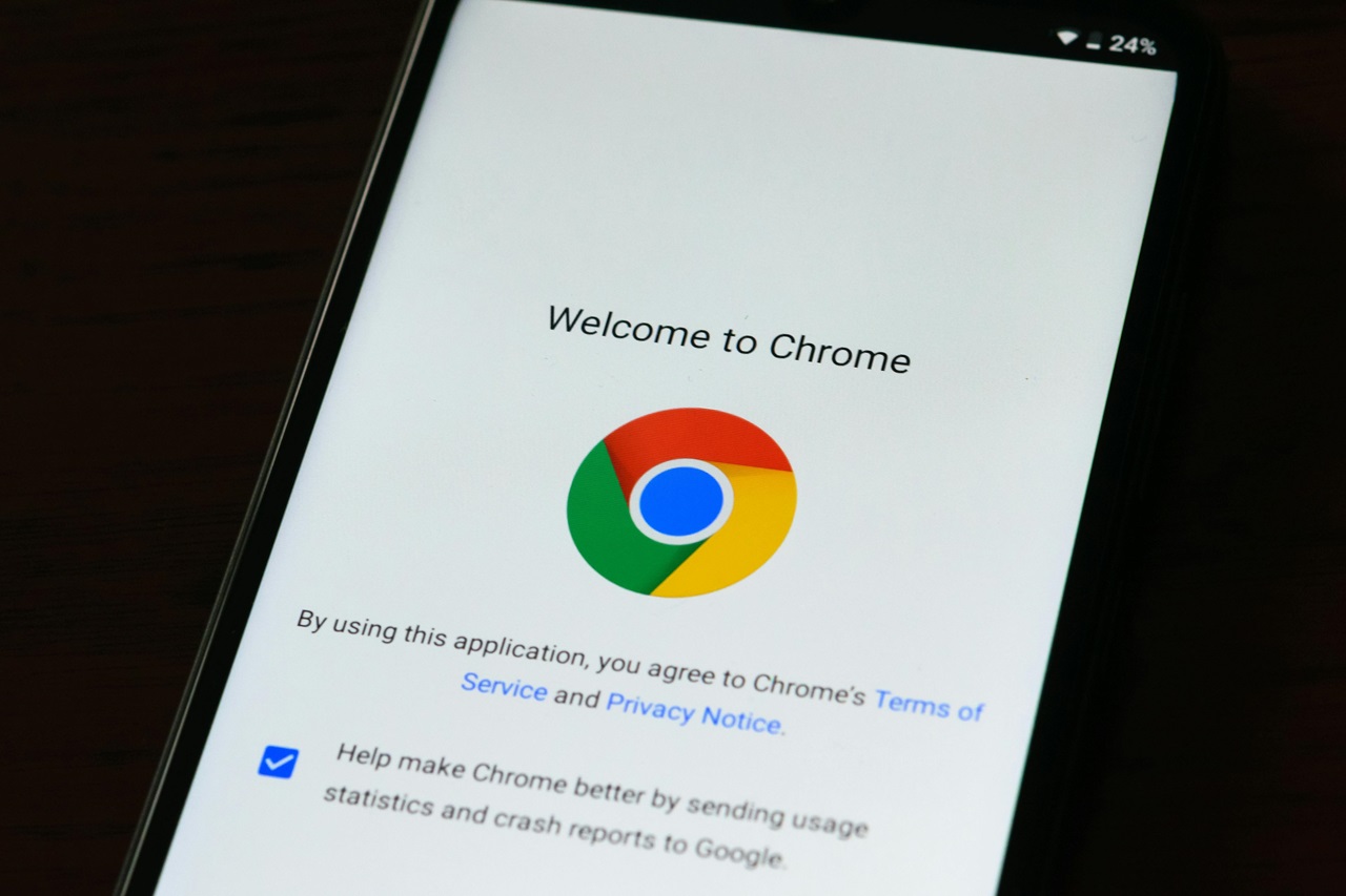 Tela de um smartphone exibindo a página de boas-vindas do navegador Google Chrome. A tela apresenta o logotipo do Chrome, que é um círculo dividido em três partes coloridas (vermelho, verde e amarelo) com um círculo azul no centro. Acima do logotipo, o texto lê 'Bem-vindo ao Chrome.' Abaixo do logotipo, há uma mensagem afirmando, 'Ao usar este aplicativo, você concorda com os Termos de Serviço e a Política de Privacidade do Chrome.' Também há uma caixa de seleção com o texto, 'Ajudar a melhorar o Chrome enviando estatísticas de uso e relatórios de falhas para o Google,' marcada indicando que o usuário concordou em enviar esses dados. O ícone da bateria no canto superior direito mostra uma carga de 24%. Imagem: créditos AS Photography / Pexels.