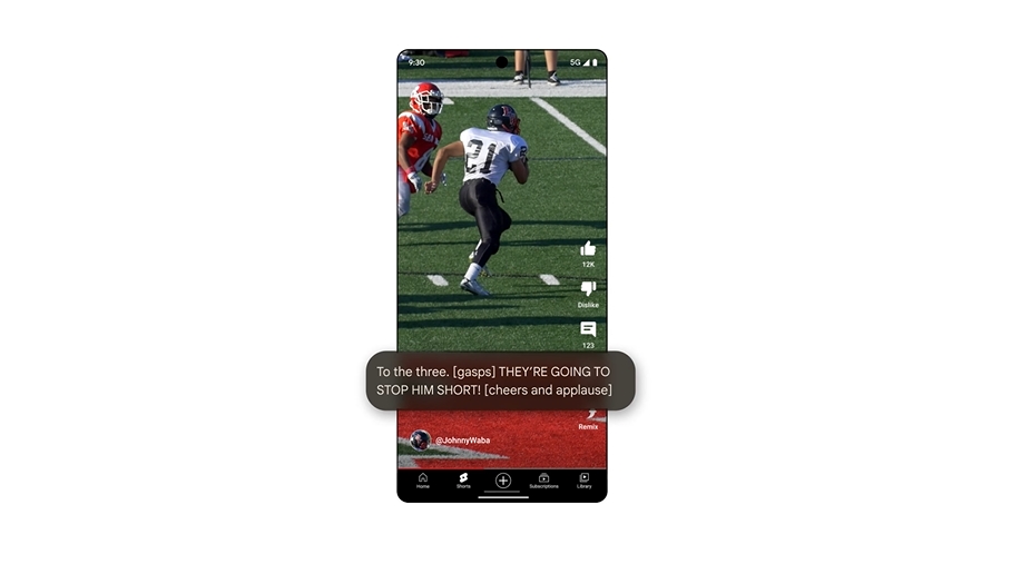 Imagem mostrando a tela de um smartphone exibindo um vídeo de futebol americano em um aplicativo de mídia social. No vídeo, um jogador de futebol americano com o número 37 está correndo com a bola, enquanto um jogador adversário tenta alcançá-lo. A tela também exibe uma legenda em tempo real que diz: 'To the three. [gasps] THEY'RE GOING TO STOP HIM SHORT! [cheers and applause]'. O nome de usuário '@JohnnyWaba' está visível na parte inferior da tela. Este exemplo ilustra o recurso Legendas Expressivas, que cria legendas em tempo real no Android, adicionando contexto emocional e sonoro às legendas. Imagem: Google divulgação.