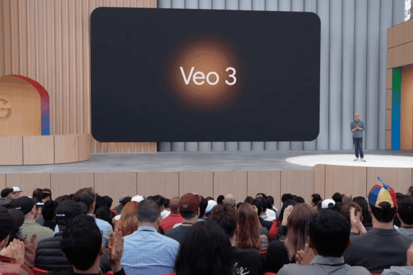 Google Veo 3: o incrível avanço da IA que gera vídeos realistas Imagem de uma apresentação da Google, onde um palestrante está em um palco com um grande telão atrás dele exibindo o texto